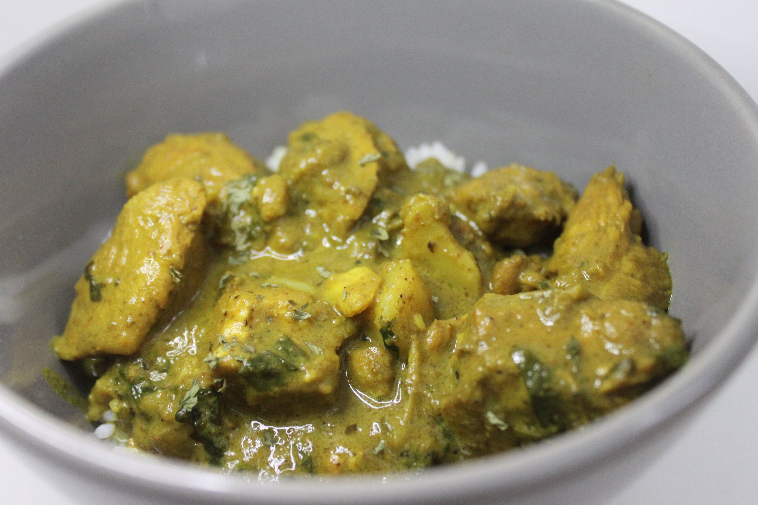 Curried chicken dish in a gray bowl on a white background